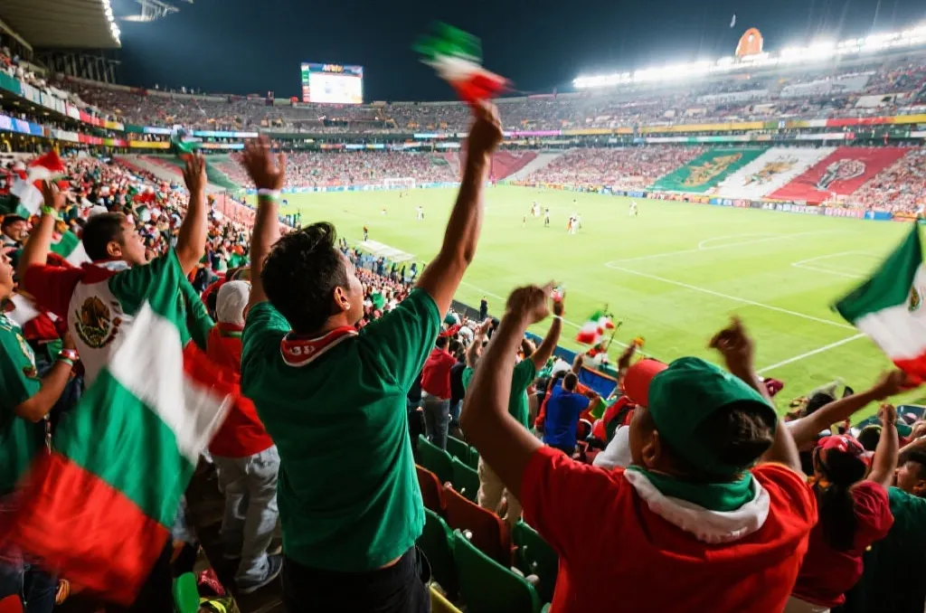 墨西哥球迷在看台上挥舞旗帜，激情洋溢